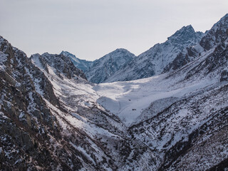 Winter landscape: a valley in the mountains among snow-capped peaks. View from a drone.