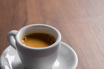 Obraz premium Fresh espresso in a white cup on walnut table with copy space