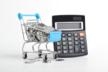 Calculator and shopping cart full of coins isolated on white background. Shopping spending concept
