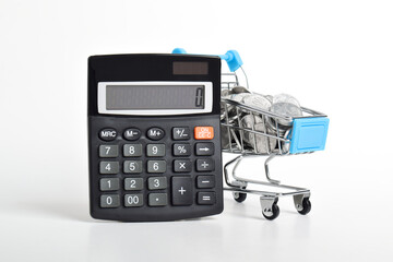 Calculator and shopping cart full of coins isolated on white background. Shopping spending concept