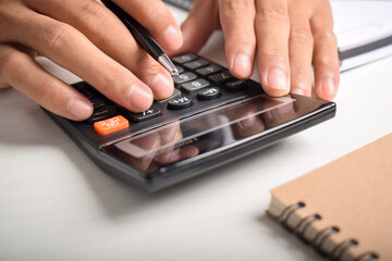 Close-up businessman's hands using calculator to calculate home finance and write notes, accounting...