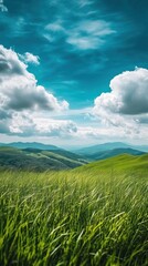 Obraz premium A serene landscape featuring rolling green hills under a bright blue sky with fluffy clouds.