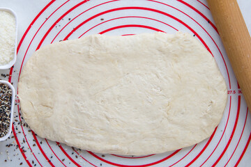 Raw dough and rolling pin on a white tablecloth, top view