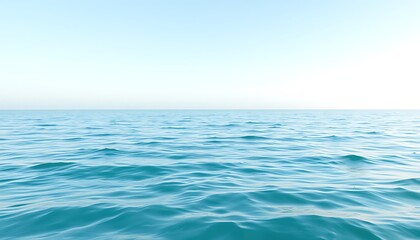 Obraz premium A tranquil seascape image featuring a calm turquoise ocean under a pale blue sky. Gentle waves ripple across the waters surface creating a peaceful and serene atmosphere.