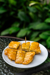 Side view of a signature dish of Pontianak, Indonesia called srikaya fried banana on a glass table