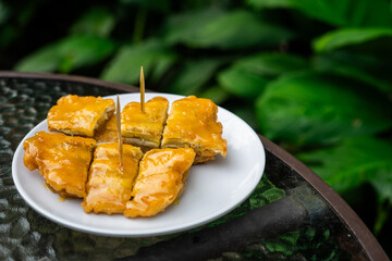 Side view of a signature dish of Pontianak, Indonesia called srikaya fried banana on a glass table