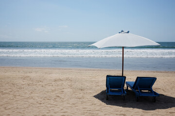 Couple lounge chairs under white umbrella on sand beach and tropical calm sea in sunny day on summer in Asian. copy space