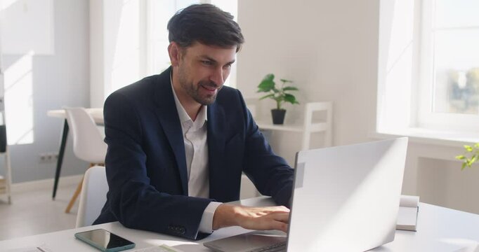 Happy businessman working in the office with a laptop and documents, showcasing professionalism while handling business tasks, audits, or accounting in an organized and joyful manner.