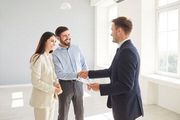 Family couple shakes hands with a real estate agent or realtor, sealing an agreement on a new home purchase. Handshake represents trust and the successful finalization of a property deal.