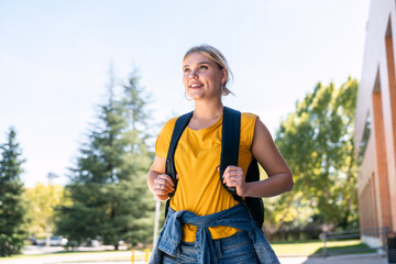 Smiling university student walking on campus on a sunny day