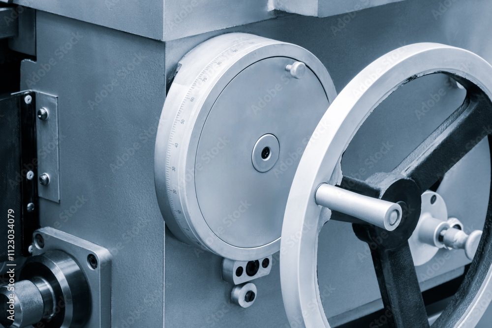 Poster A lathe machine with a white handle and a silver wheel. The handle is attached to a machine that is used to cut metal