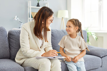 Doctor psychologist conducts a therapy session with a young girl, engaging in a conversation and...