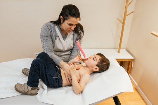 Physiotherapist assisting young boy with respiratory physiotherapy using pep mask
