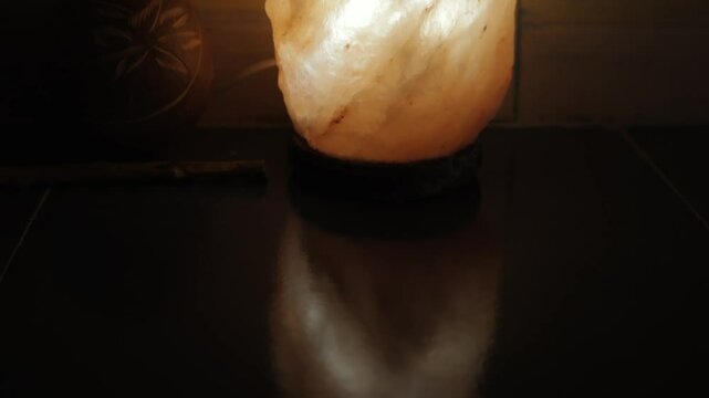 Tantra Massage Practice. Salt lamp resting on a dark surface casts a warm glow, creating a cozy and inviting ambiance.Element of Tantra Massage in Oriental Culture