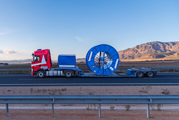 Truck with a semi-trailer designed for special transports, carrying a large coil used for...