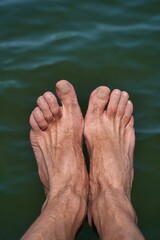 Relaxed feet of a man against the background of water 