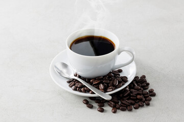 Fototapeta premium ホットコーヒーとコーヒー豆 A cup of hot coffee poured into a white cup with coffee beans.