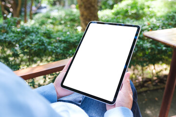 Mockup image of a woman holding digital tablet with blank white desktop screen in the outdoors