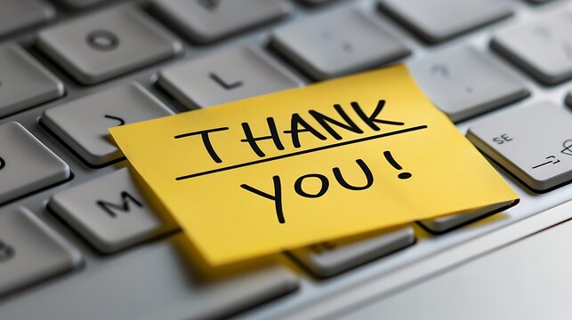 A yellow sticky note with "THANK YOU!" written on it sits on a keyboard, conveying appreciation and gratitude in a digital workspace.
