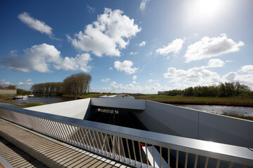 Modern bridge over highway and canal, sunny day.  Clear blue sky with puffy clouds.  Elevated...