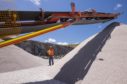 Man walking in between piles of aggregates near the crusher.