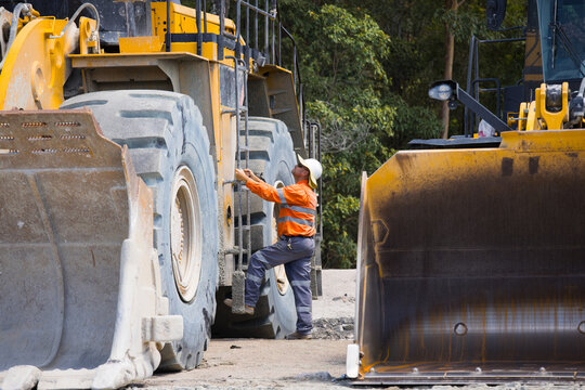 Man climbing up the payloader truck in a quarry.