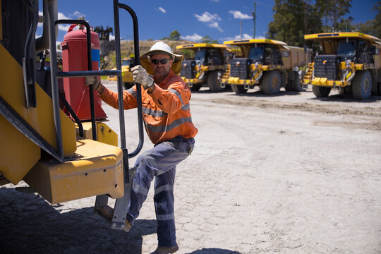 Mining operator man holding on the handrails while climbing up the dump truck