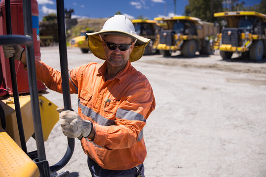 Mining operator man holding on the handrails while climbing up the dump truck