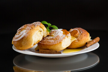 Baked goods. Sweet buns with cottage cheese filling and honey in a plate isolated on a black...