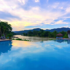 Fototapeta premium Serene riverside retreat with palm trees clear blue sky and infinity pool reflection