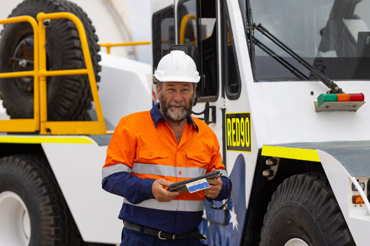 man working on the digital tablet beside oversize crane truck on industrial site