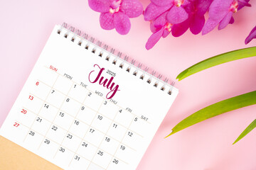 Desk calendar for July 2025 with blooming pink orchid.
