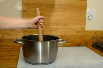 Cooking in a metal pot on an induction hob, a large wooden spoon for stirring