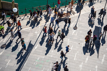 Looking down at pedestrians and their shadows along the waterfront at Circular Quay