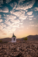 small cute white wooden chapel in a barren volcanic landscape. Sunrise, landscape shot of Ermita...