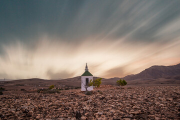 small cute white wooden chapel in a barren volcanic landscape. Sunrise, landscape shot of Ermita...
