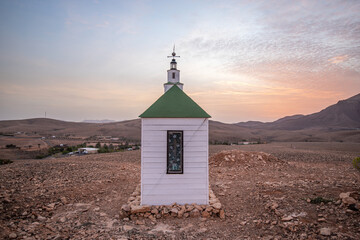small cute white wooden chapel in a barren volcanic landscape. Sunrise, landscape shot of Ermita...