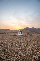 small cute white wooden chapel in a barren volcanic landscape. Sunrise, landscape shot of Ermita...
