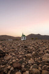 small cute white wooden chapel in a barren volcanic landscape. Sunrise, landscape shot of Ermita...