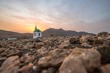 small cute white wooden chapel in a barren volcanic landscape. Sunrise, landscape shot of Ermita...