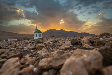 small cute white wooden chapel in a barren volcanic landscape. Sunrise, landscape shot of Ermita...