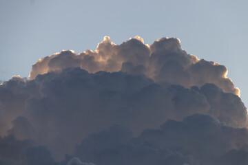 Fluffy cloud formation illuminated by sunlight, creating a serene and majestic atmosphere against a...