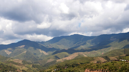 Scenic landscape featuring lush hills and dramatic clouds over a mountain range