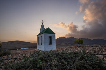 small cute white wooden chapel in a barren volcanic landscape. Sunrise, landscape shot of Ermita...