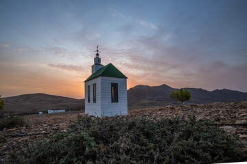small cute white wooden chapel in a barren volcanic landscape. Sunrise, landscape shot of Ermita...