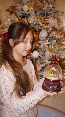 beautiful girl with snow globe under the xhristmas tree