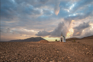small cute white wooden chapel in a barren volcanic landscape. Sunset, landscape shot of the Ermita...