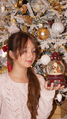 beautiful girl with snow globe under the xhristmas tree