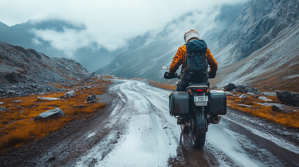 Obraz premium A motorcyclist rides on a dirt road in the mountains. Cloudy weather. Off-road enduro touring 