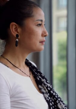Pensive Middle-Aged Asian Woman Gazing Out the Window: A Moment of Reflection